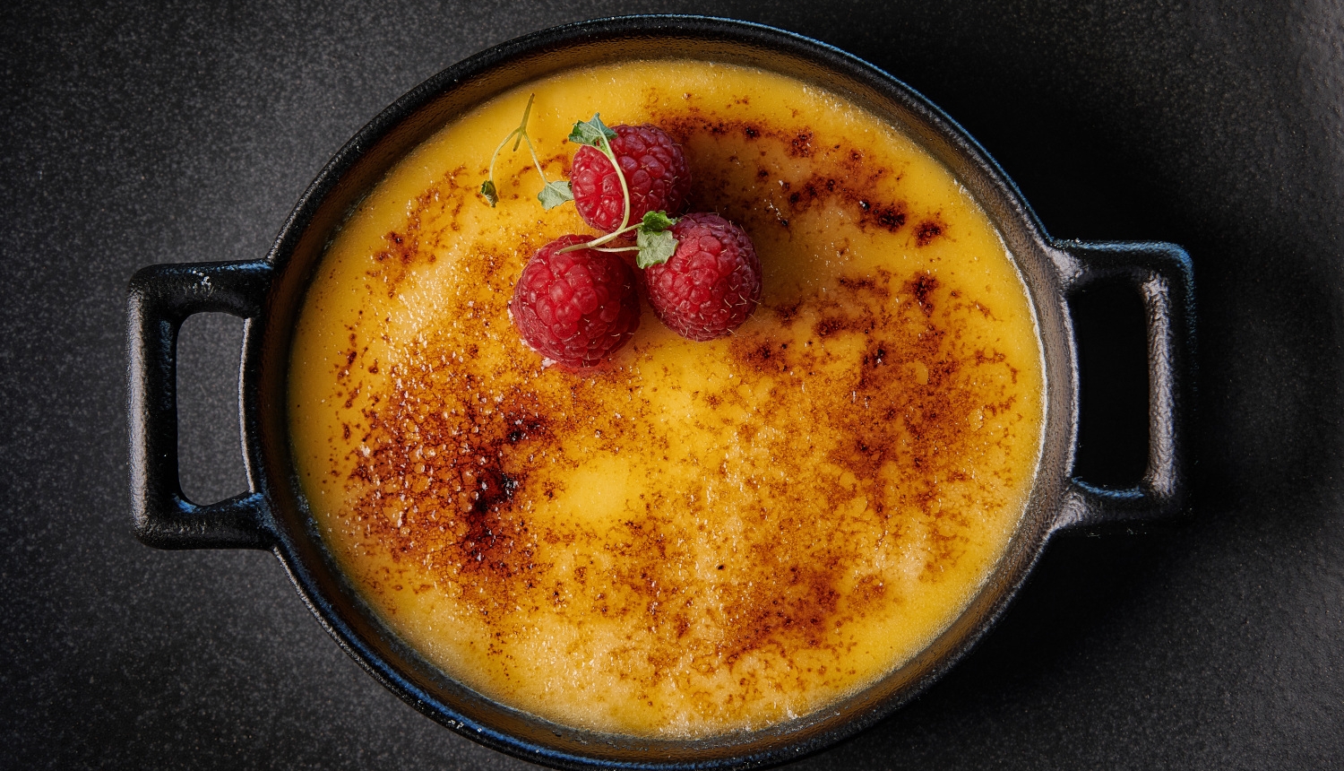 A creme brulée dessert topped with raspberries