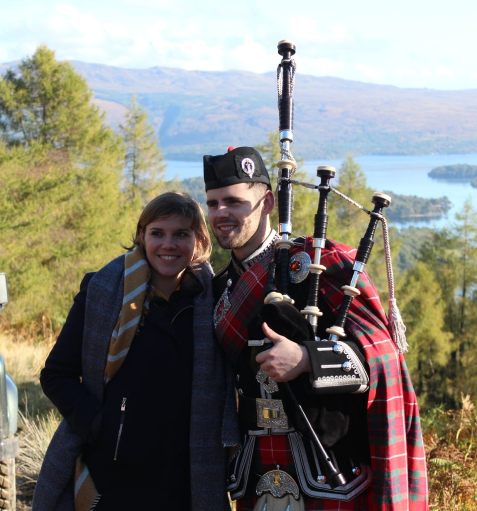 a man and woman getting their picture taken while standing outside and holding bagpipes