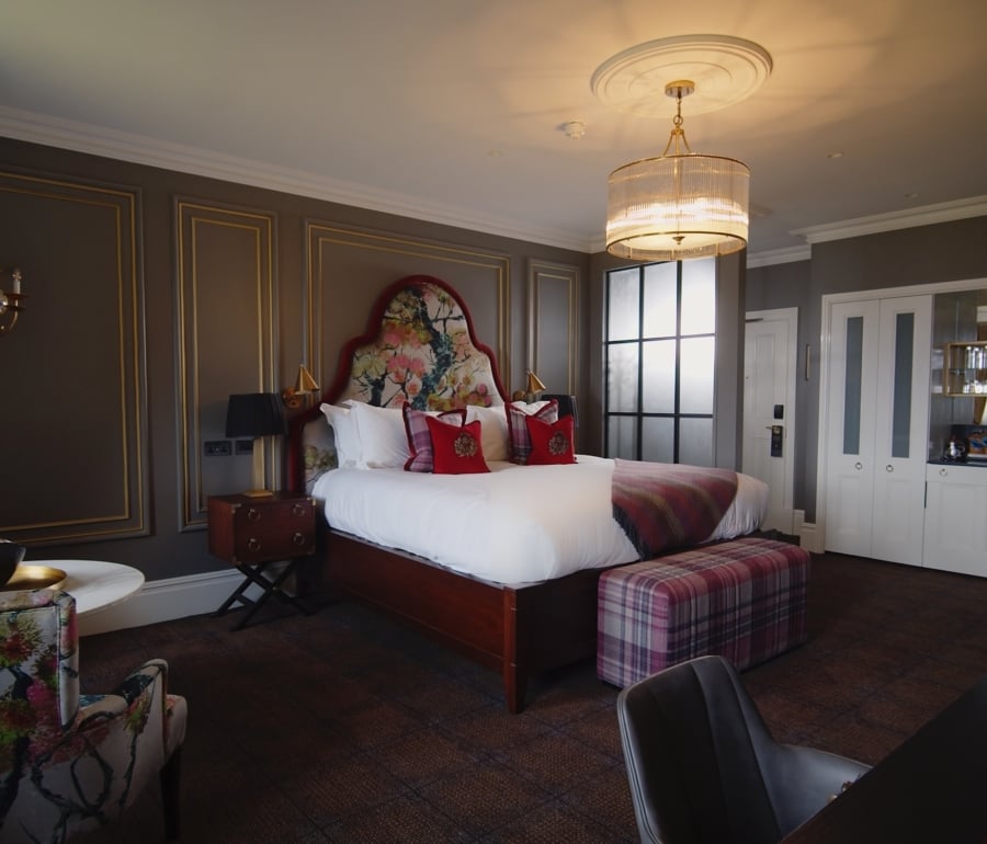 The bedroom of the Tower Suite at Cameron House with a seating bench at the end of the bed.