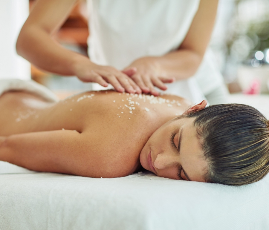 a woman laying on a table getting an exfoliating massage treatment on her back