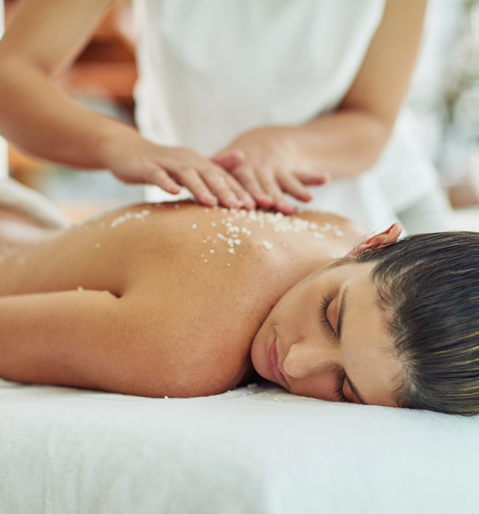 a woman laying on a table getting an exfoliating massage treatment on her back