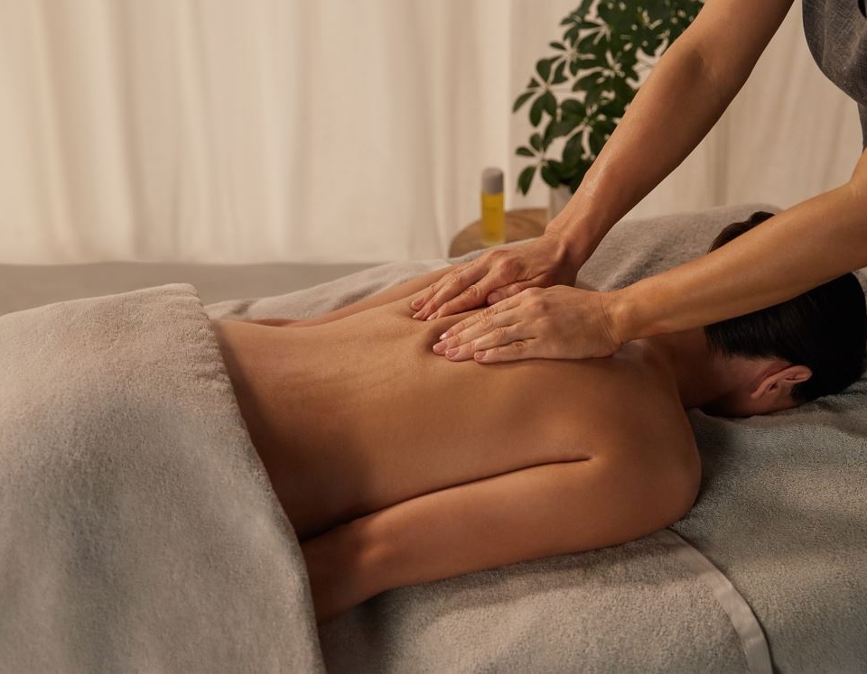 a woman laying face down getting her shoulders massaged