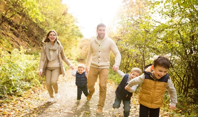 a family walking down a trail in the forest laughing on a sunny day