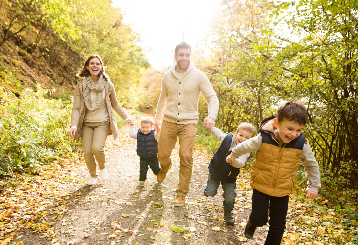 a family walking down a trail in the forest laughing on a sunny day