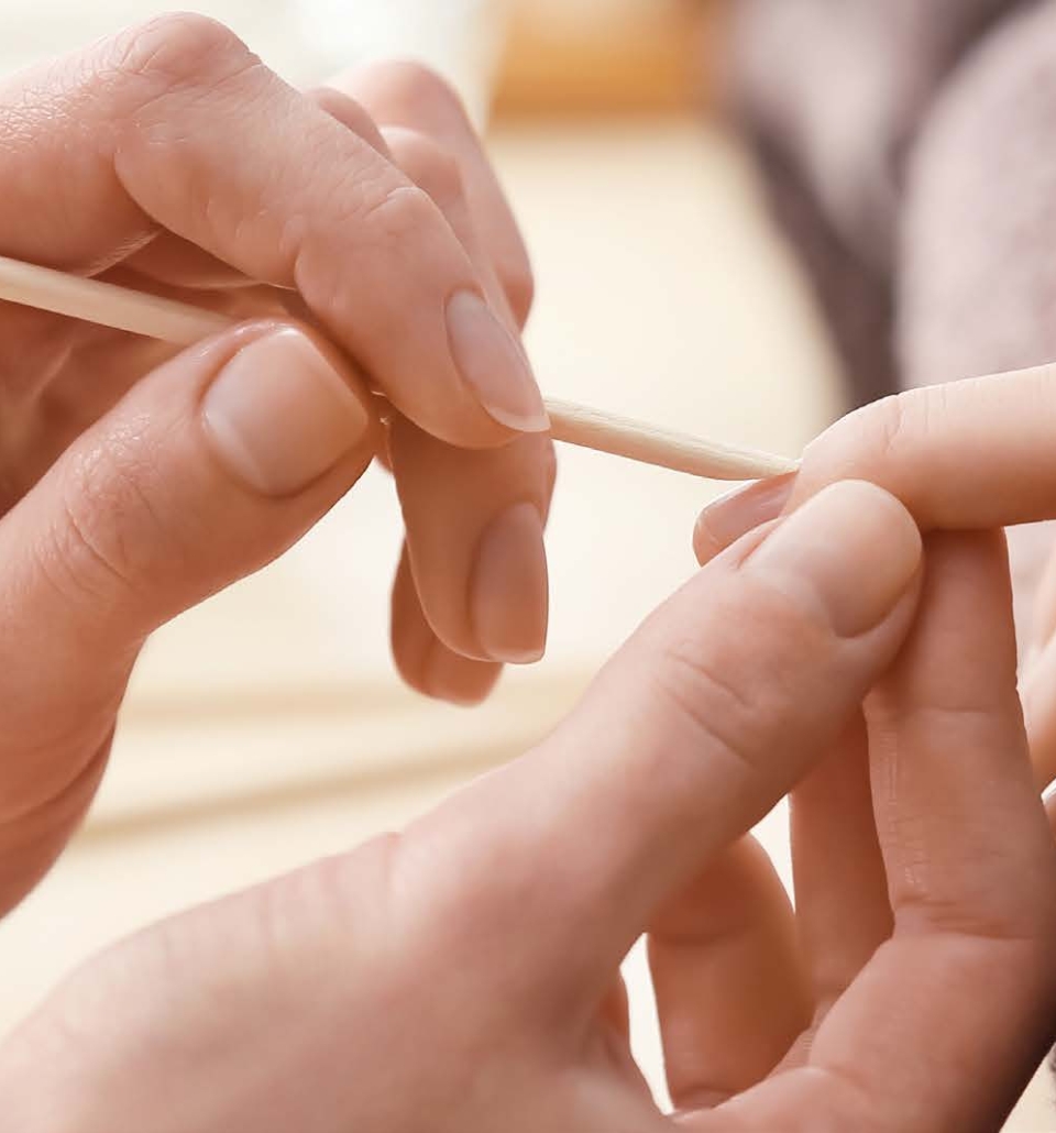a person getting a nail their nails cleaned with a wooden stick