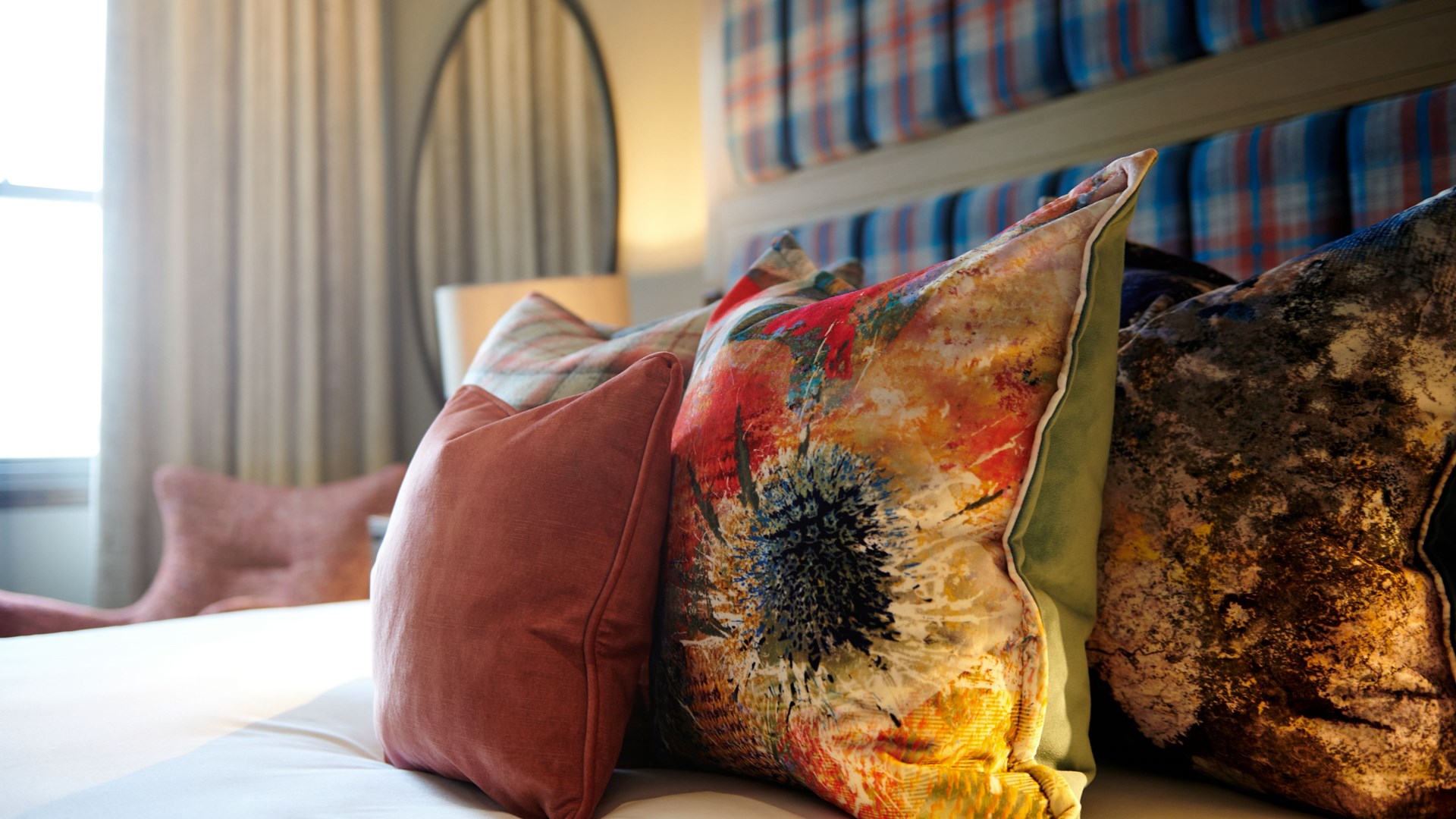 Colourful hotel room pillows with flowers.