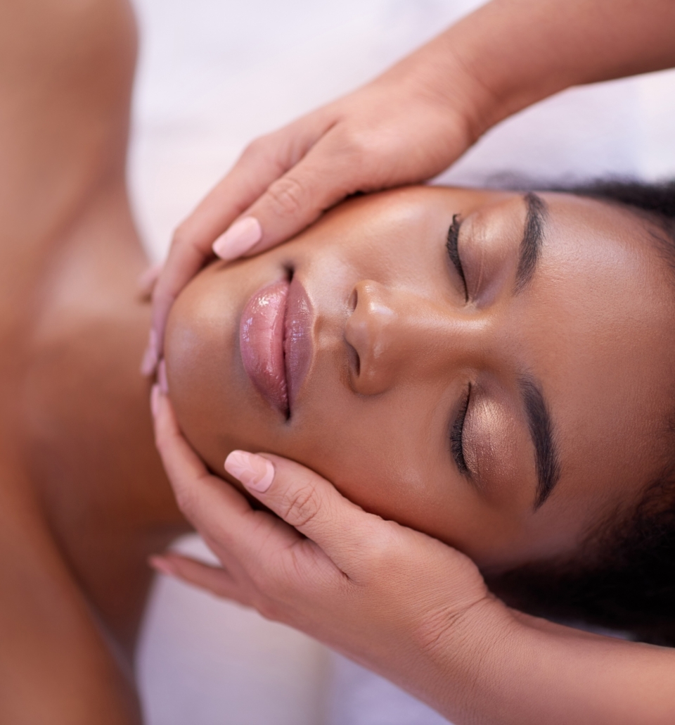 a woman laying under a towel getting her face massaged