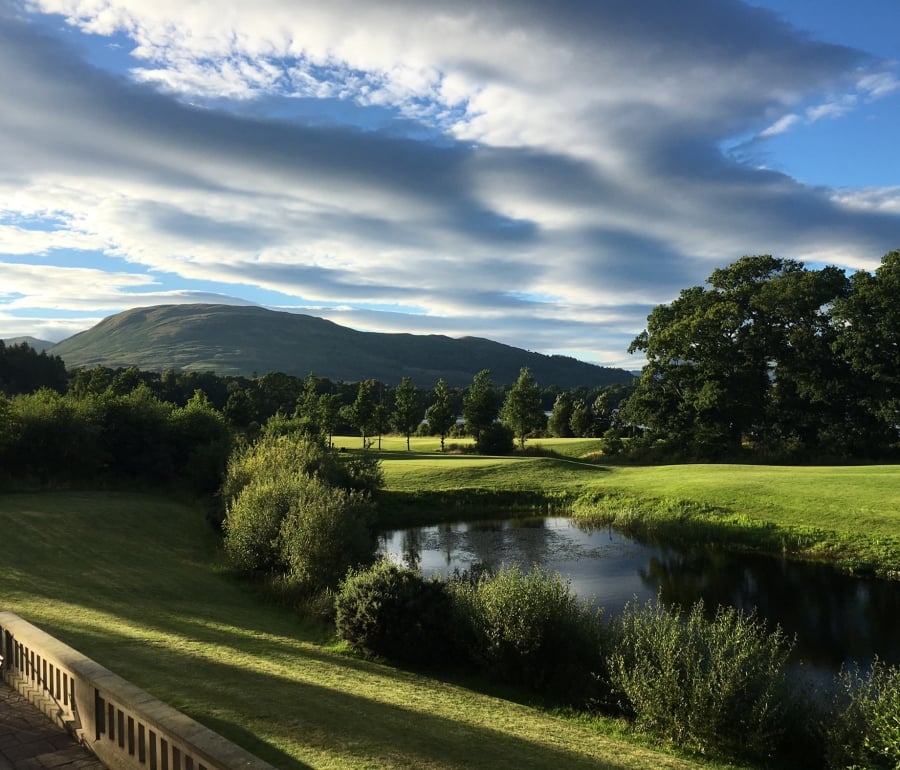 a view from cameron house over looking the green grass and a large mountain in the back