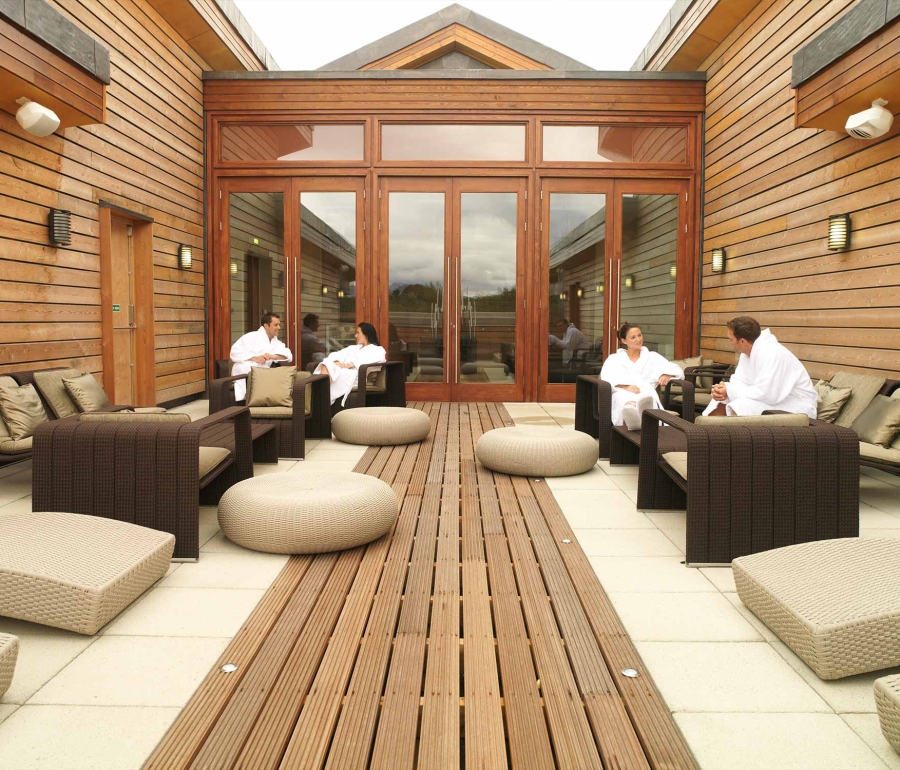 people sitting outside in robes enjoying the sun in the spa area