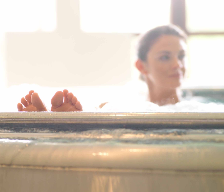 a woman sitting in a whirlpool with her feet on the edge