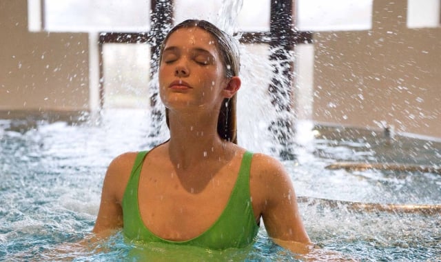 a woman in a pool getting splashed by flowing water