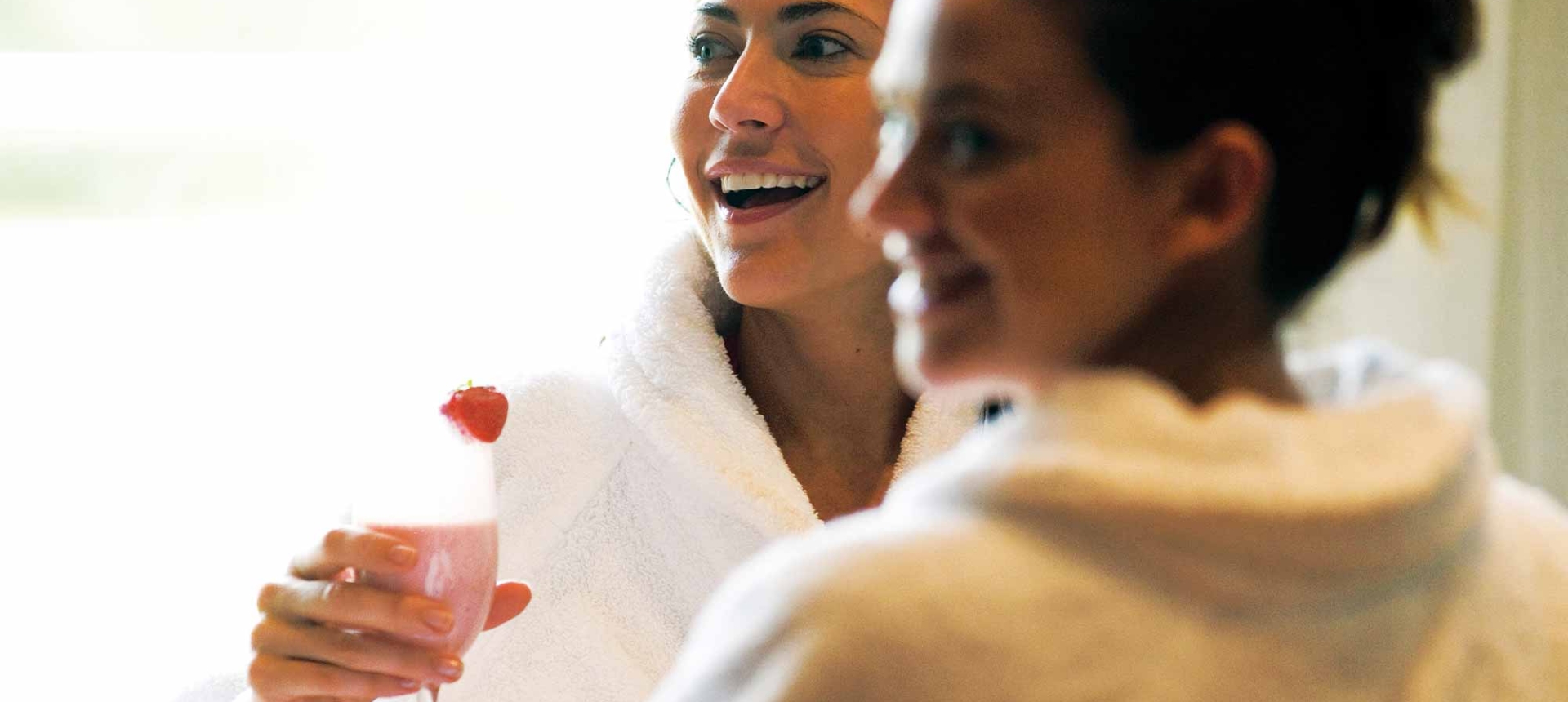 two woman enjoying a spa day and drinking a pink drink