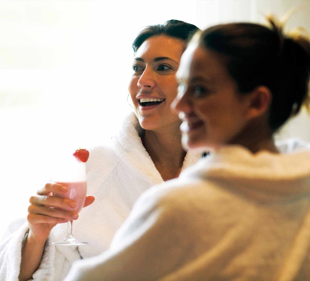 two woman enjoying a spa day and drinking a pink drink