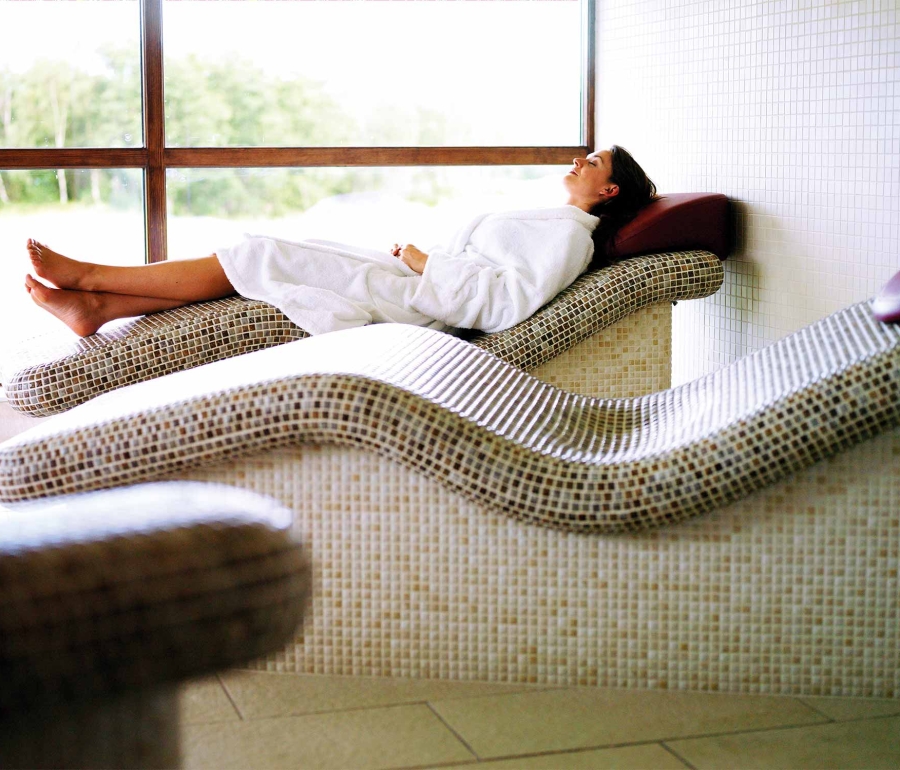 a woman relaxing on a tile chair enjoying the sun shine coming in from the out side