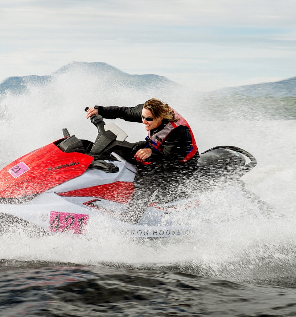 a person riding on a red jet ski splashing water in the middle of the lake