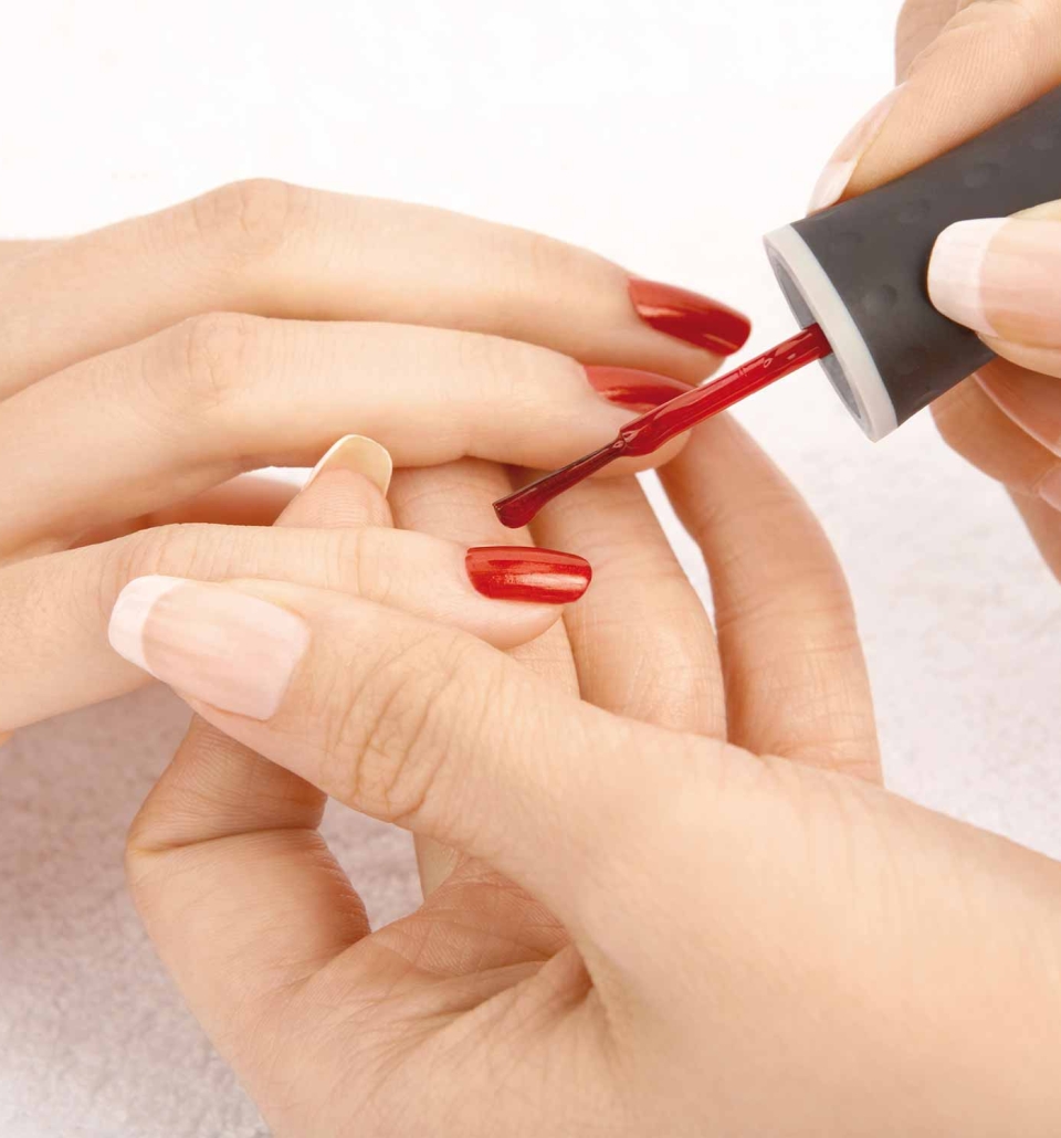a person applying red nail polish to a set of nails
