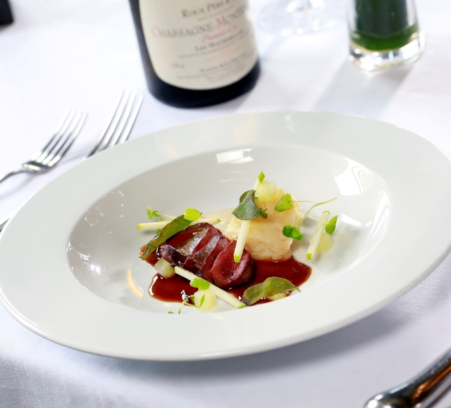 sliced up duck sitting on a plate with colourful garnish