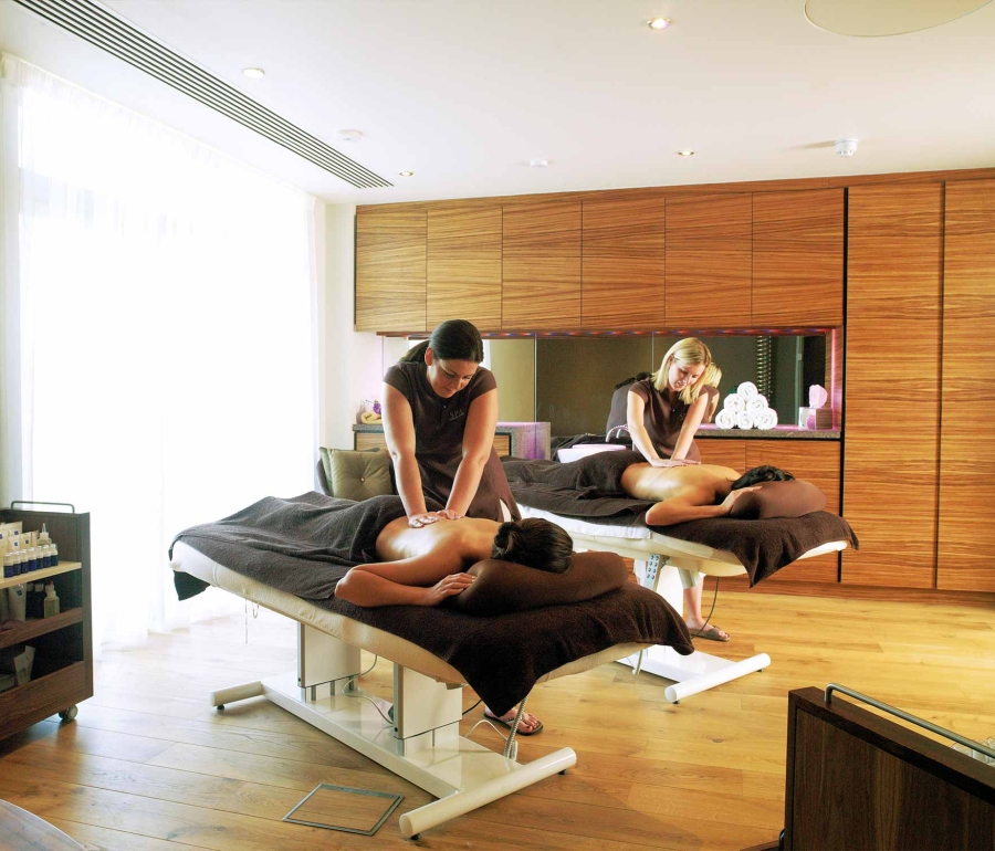 two people getting massages by spa workers in a spa suite