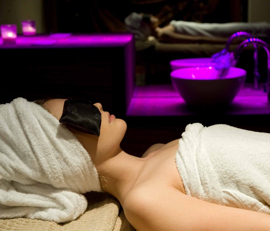 woman relaxing in a spa with a mirror in the background and pink lighting