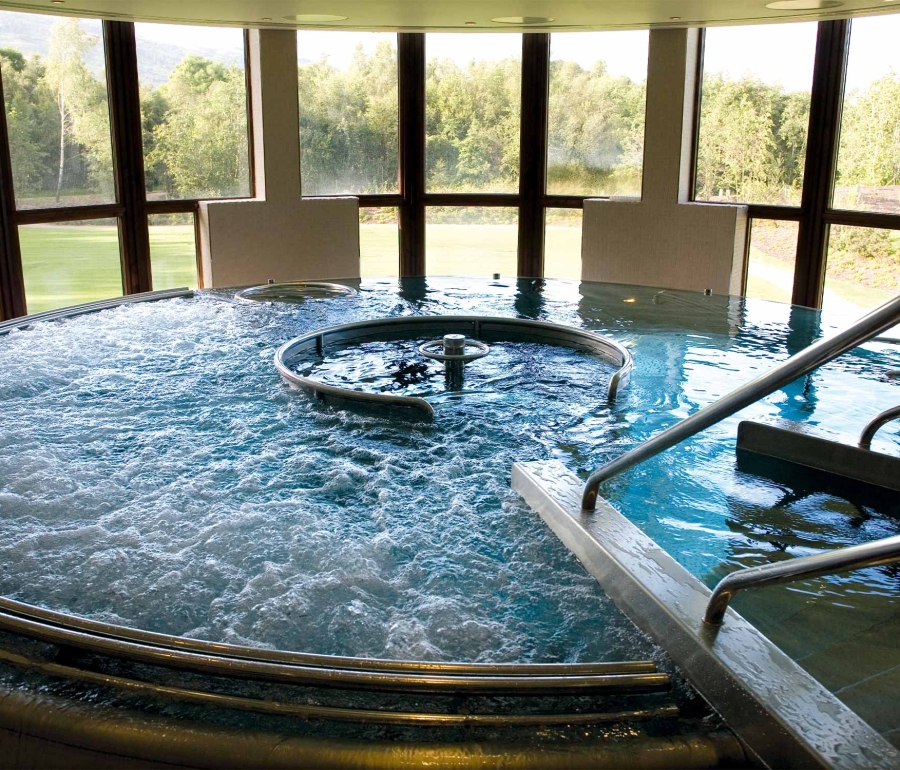 a large whirl pool with windows looking outside at the trees