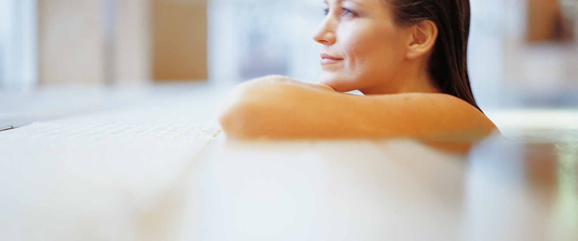 a woman sitting in a pool leaning on the edge looking outside