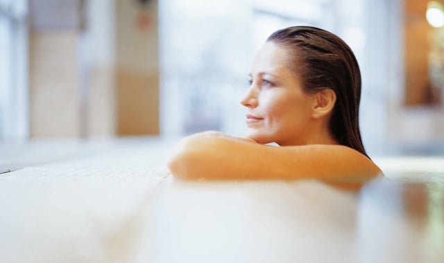 a woman sitting in a pool leaning on the edge looking outside