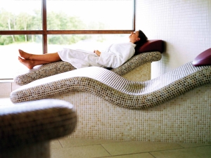 a woman laying down in a robe relaxing on a spa bed