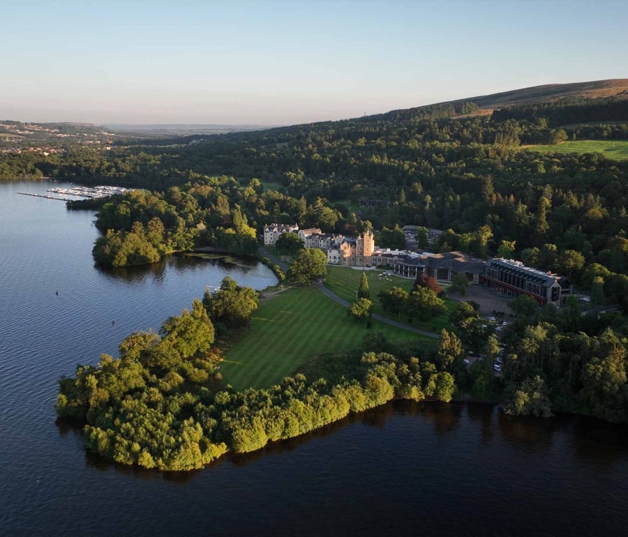 a birds eye view of cameron house with lots of trees and hills behind it