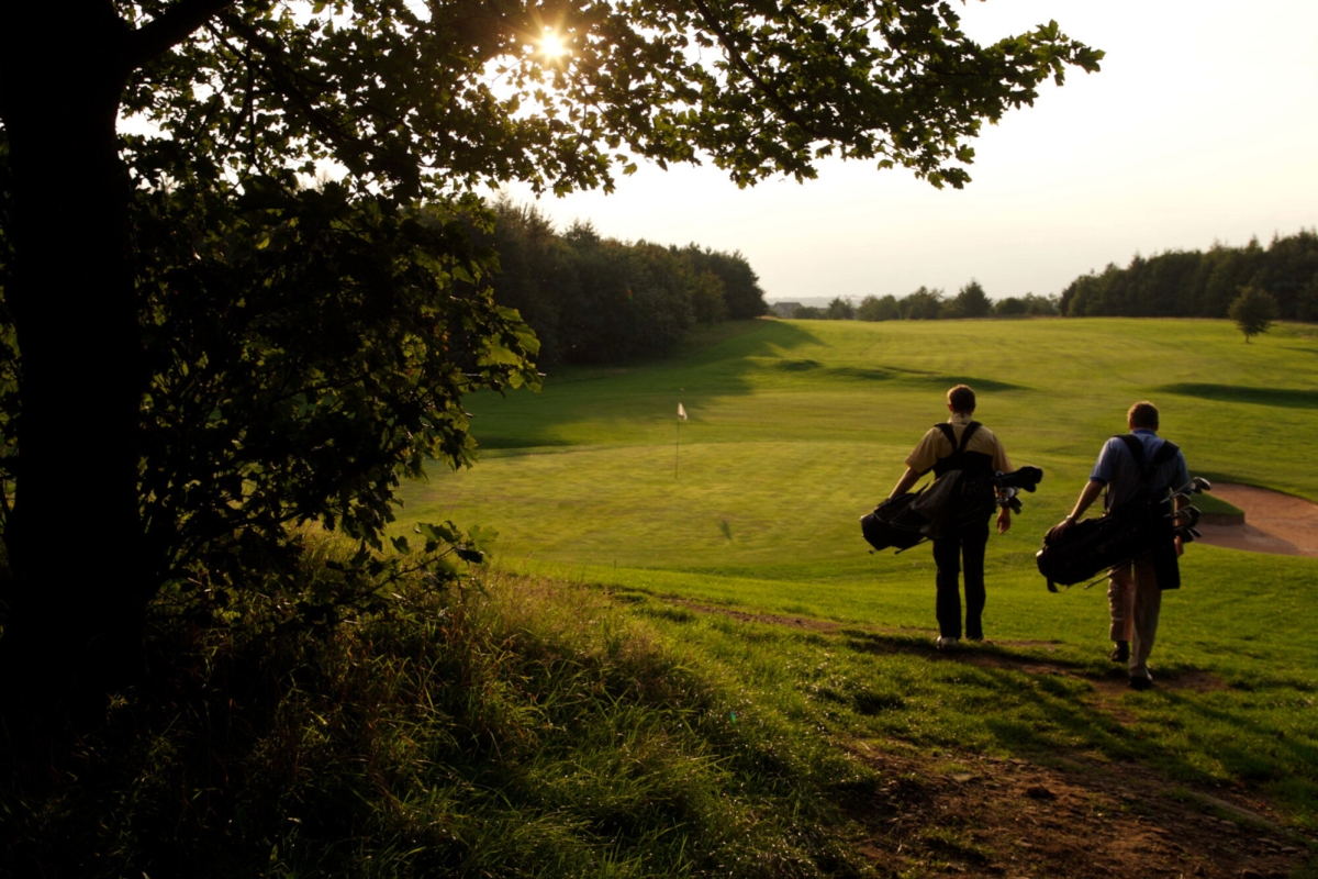 Two golfers walking down the fairway into the sunset at The Carrick championship golf course at Cameron House Loch Lomond