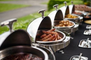 multiple steam tables with food inside sitting on a table outside