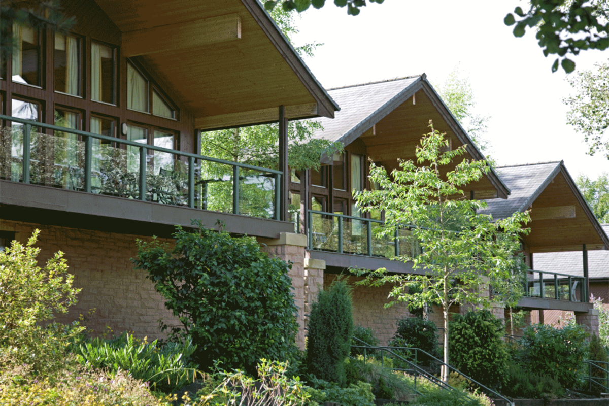 three cottages with trees below them and stairs leading up to the entrance