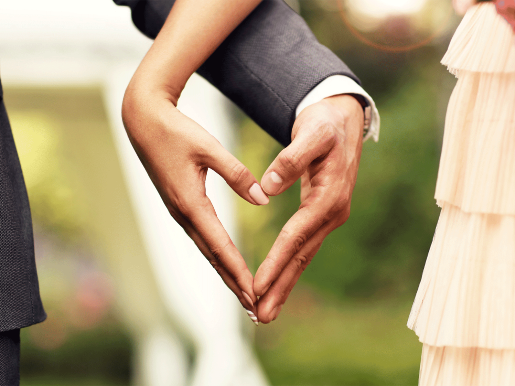 a bridge and groom making a heart with their hands