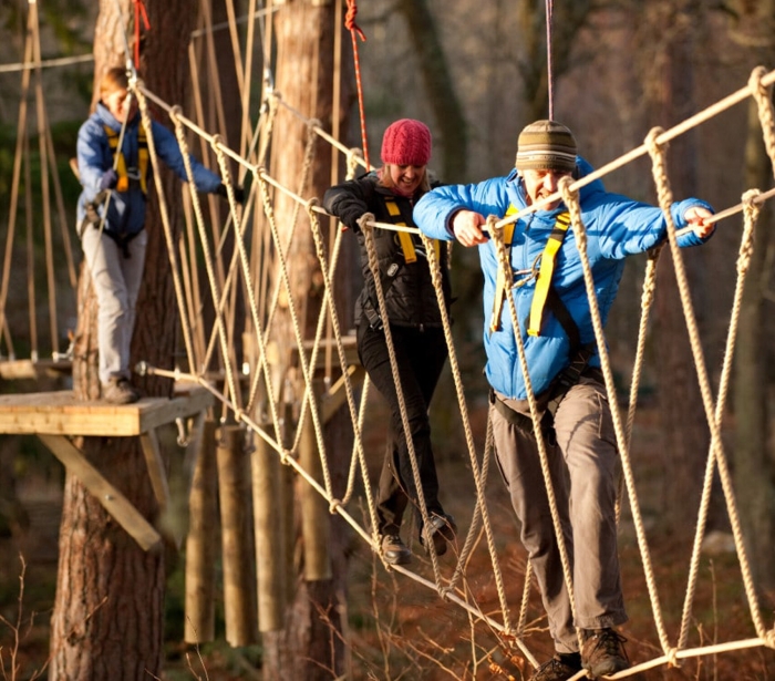 three people walking across a rope bridge