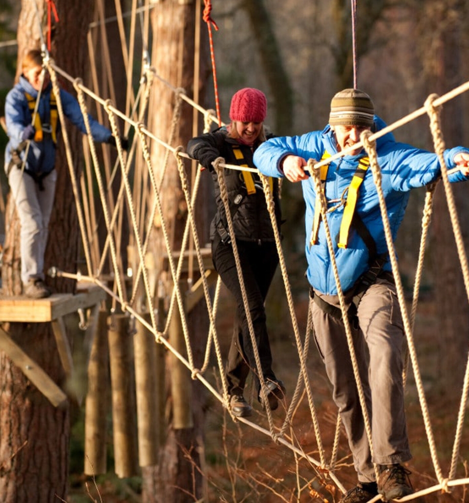 three people walking across a rope bridge