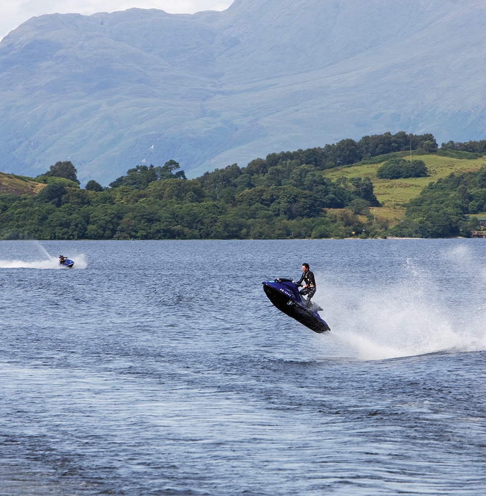 a person on a blue and black jet ski jumping high over the waves in the lake