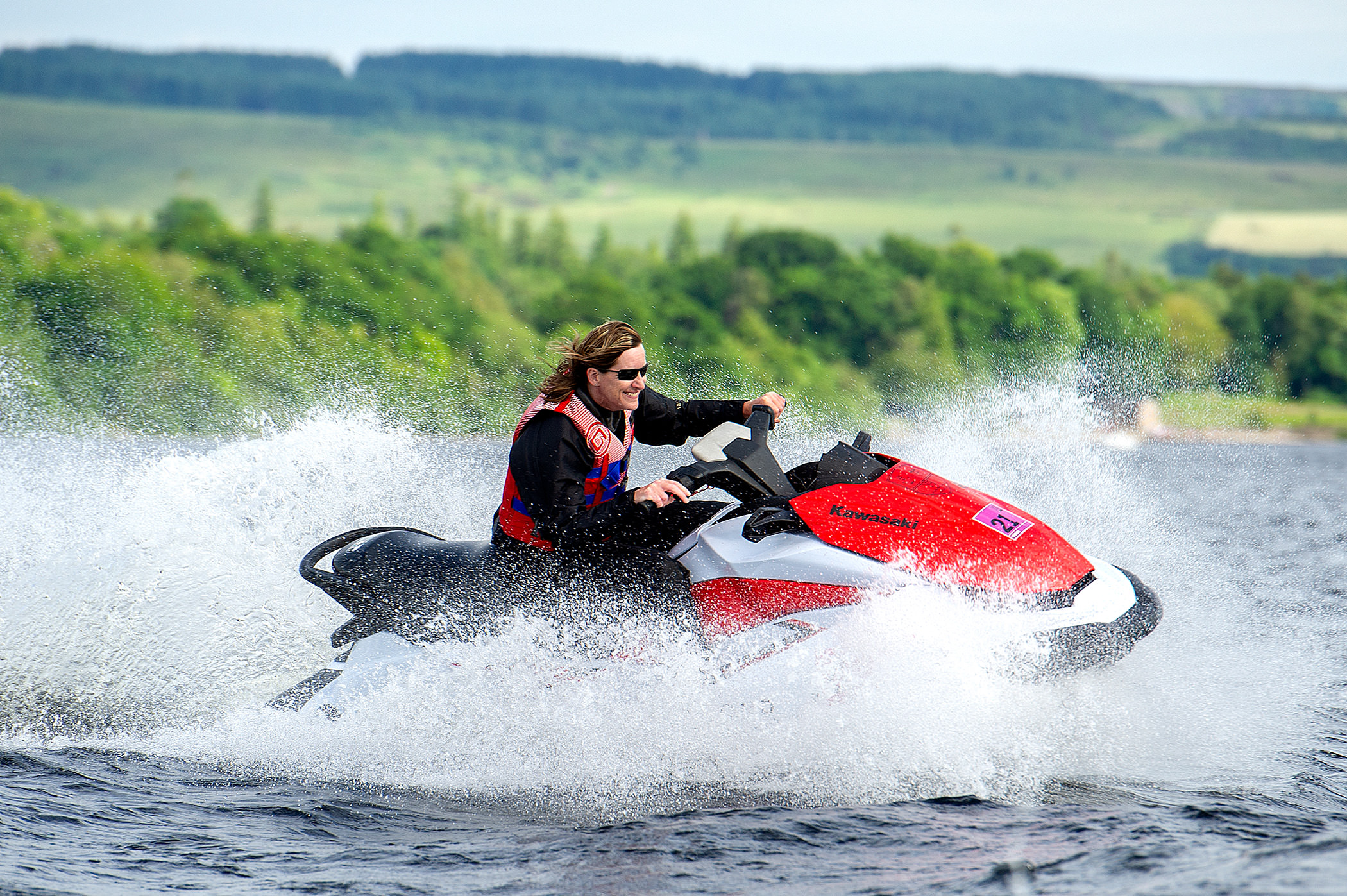 a person riding on a jet ski on the water with a beautiful green forest in the back ground