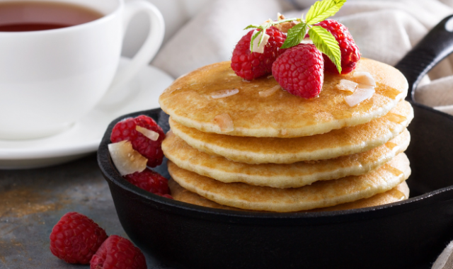 a skillet with pancakes inside and raspberries on top and the side