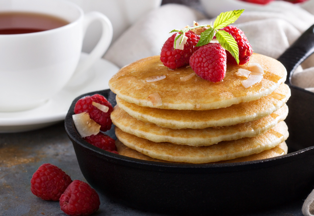 a skillet with pancakes inside and raspberries on top and the side