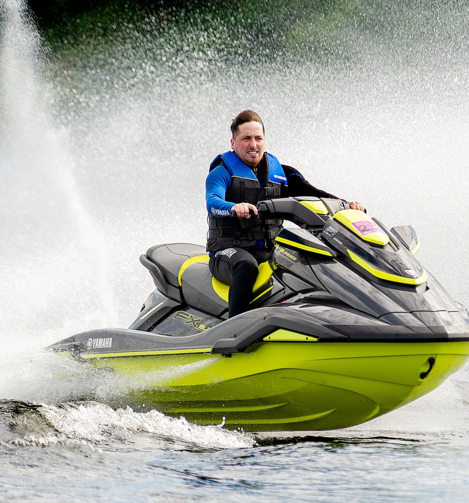 a man riding a black and lime green jet ski wearing a blue life jacket in the water