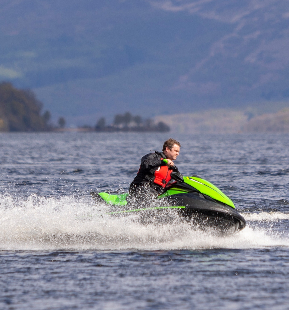 a man riding a bright green and black jet ski on the water