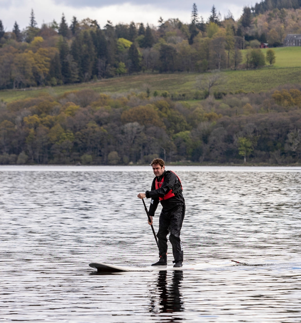 a man standing up on a paddle board paddling in the middle of the water