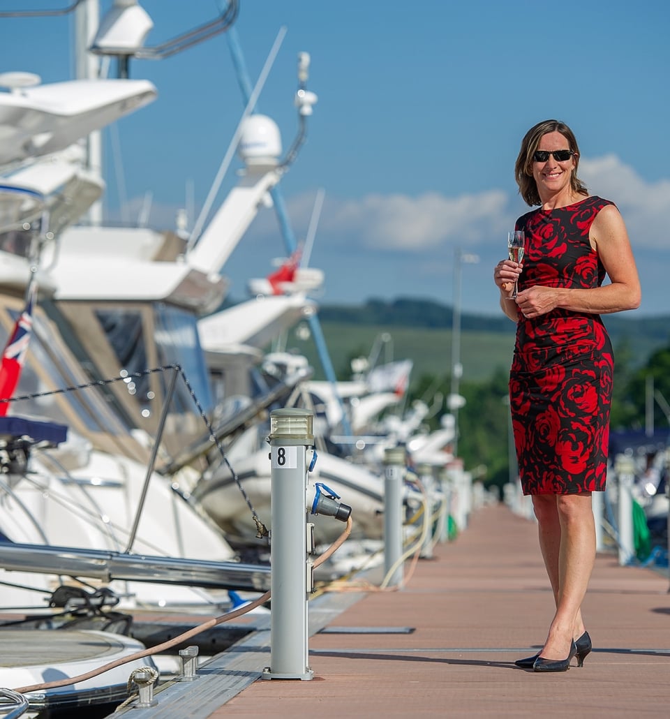 a woman standing on a marina dock wearing a red and black floral dress