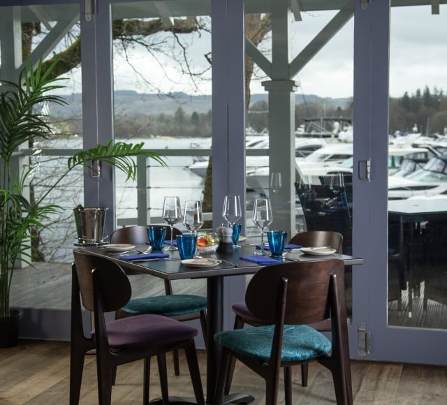 A window view of the marina with a table and four chairs at La Vista restaurant.