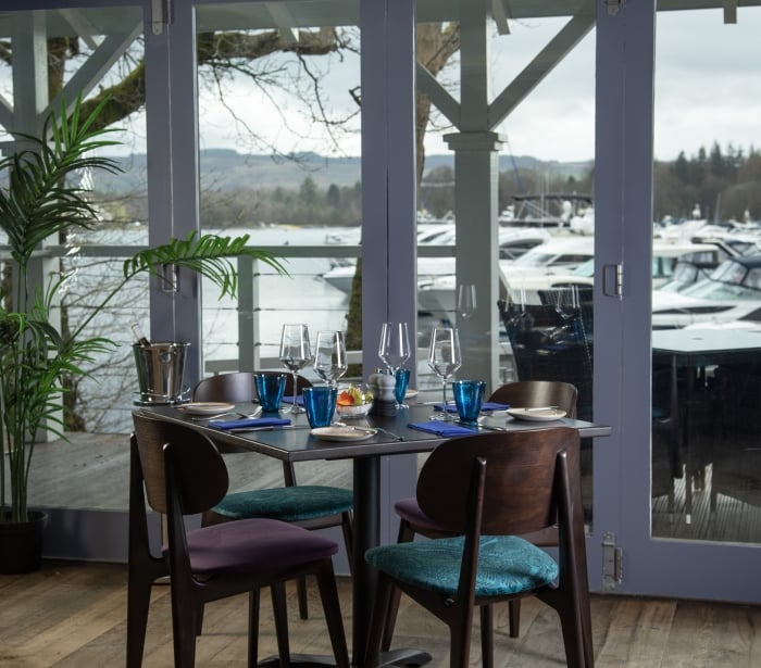 A window view of the marina with a table and four chairs at La Vista restaurant.