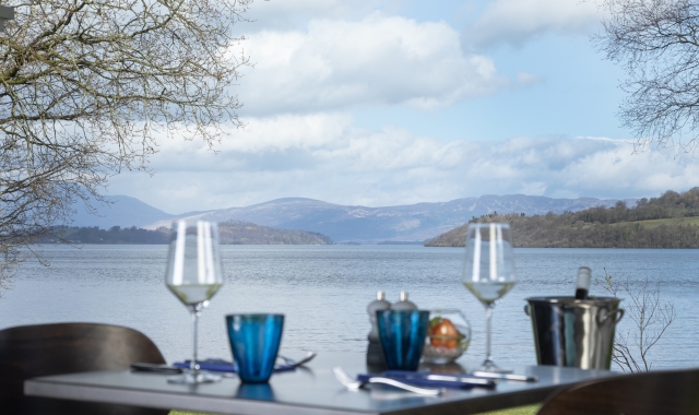 Dining table set with two glasses and a plate at La Vista restaurant by Loch Lomond.