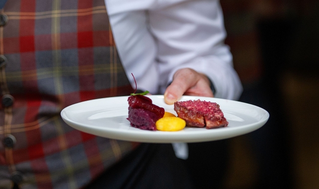 a server holding a plate with food items