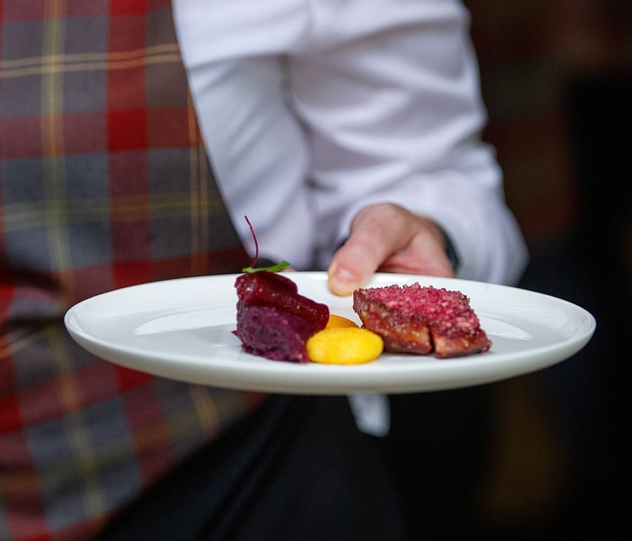 a server holding a plate with food items