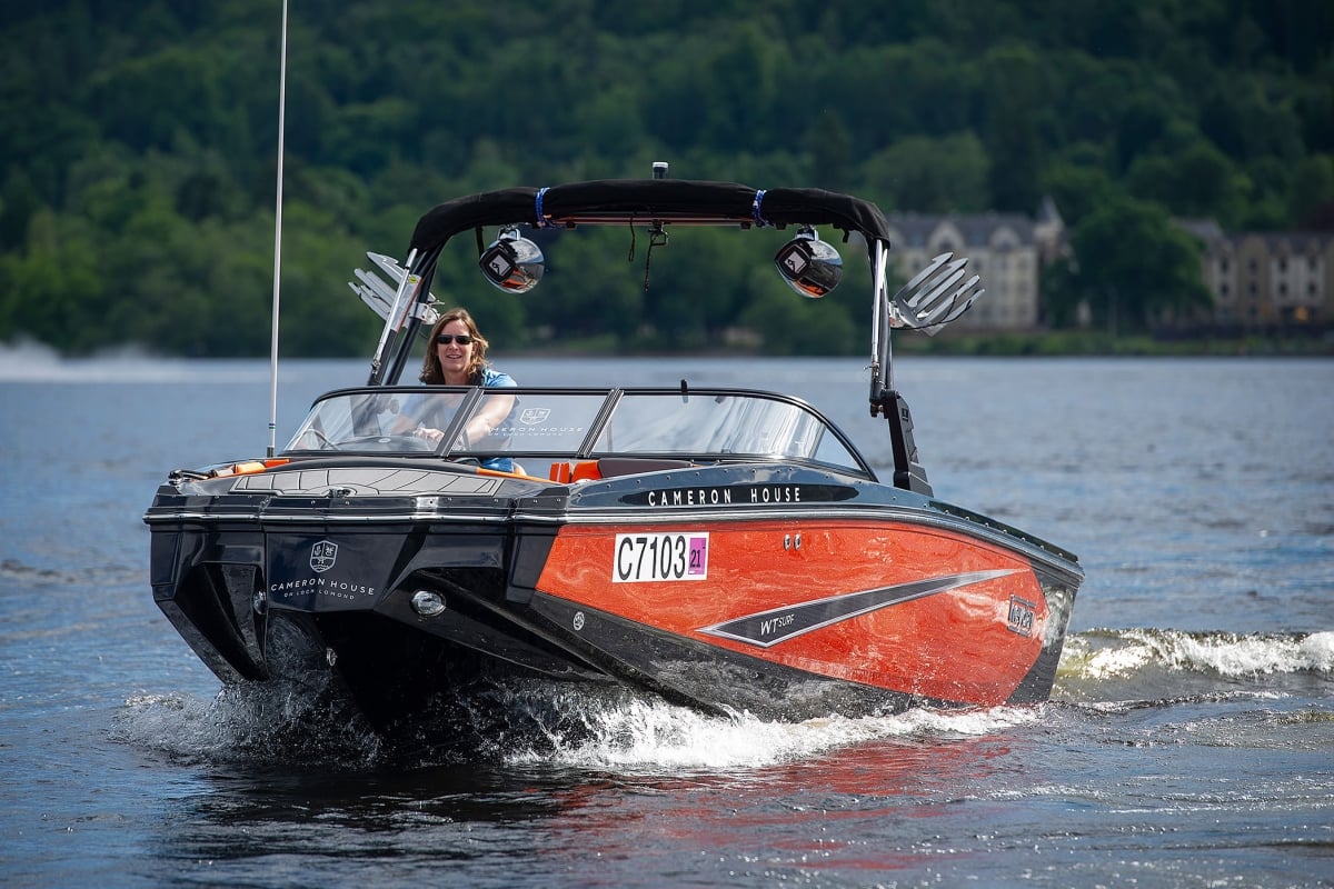 a woman riding on a red and black boat in the water enjoying her day