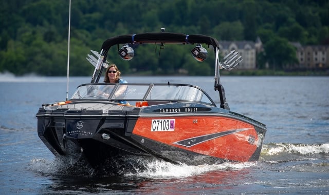 a woman riding on a red and black boat in the water enjoying her day