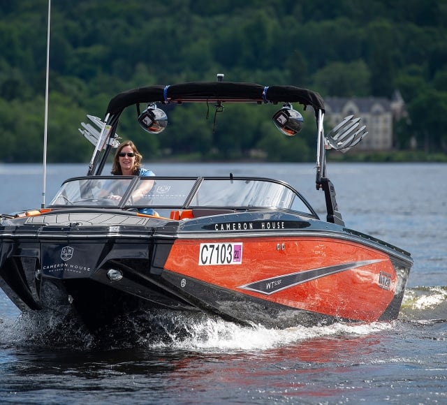 a woman riding on a red and black boat in the water enjoying her day